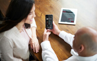 HVAC technician showing a homeowner how to adjust her smart thermostat from her phone