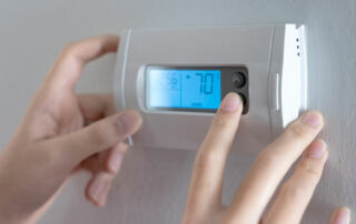 woman adjusting her thermostat