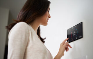 woman adjusting her smart thermostat